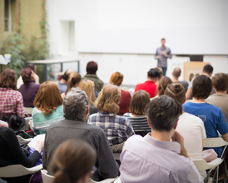 Diversas personas toman nota y atienden desde sus asientos a la exposición de un conferenciante